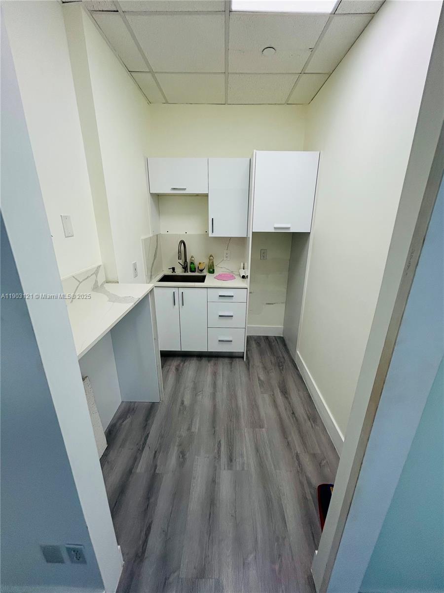 A small kitchenette features white cabinets, a sink, and gray wood-look flooring — 10305 NW 41st St # 216, Doral FL 33178, DORAL, FL