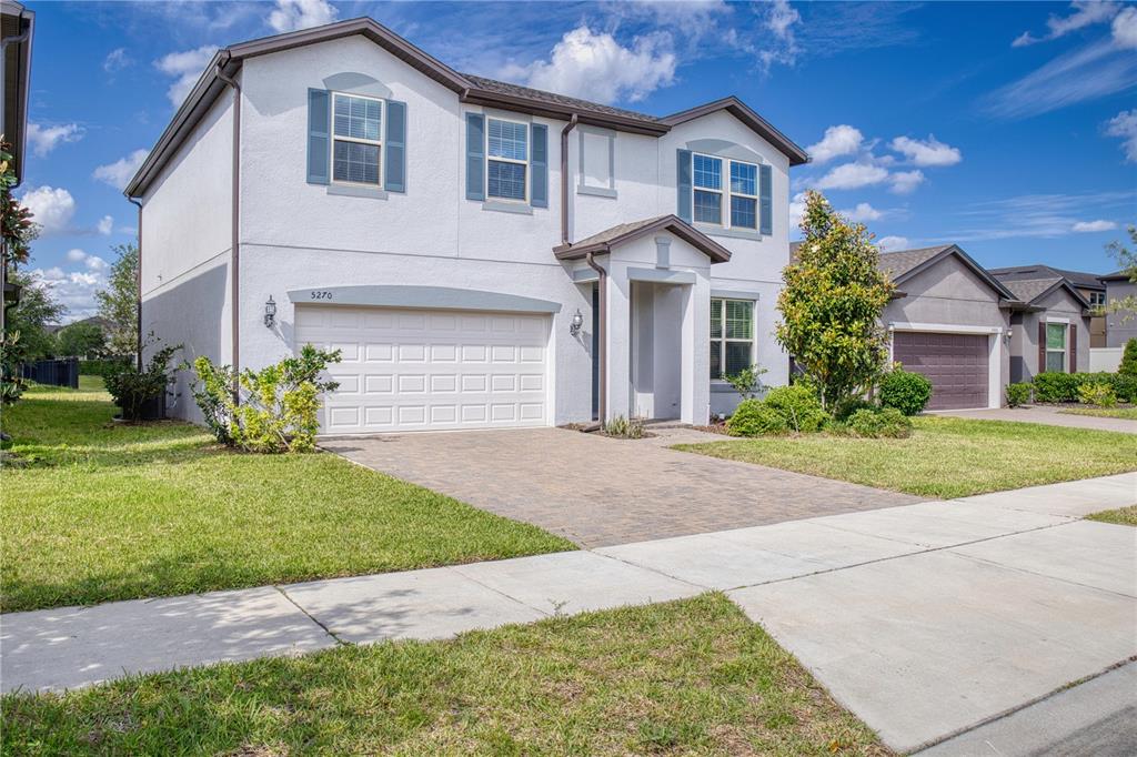 A two-story suburban house with a white stucco facade, blue shutters, and a paved driveway — 5270 BRYDON WOODS CIRCLE, ST CLOUD, FL