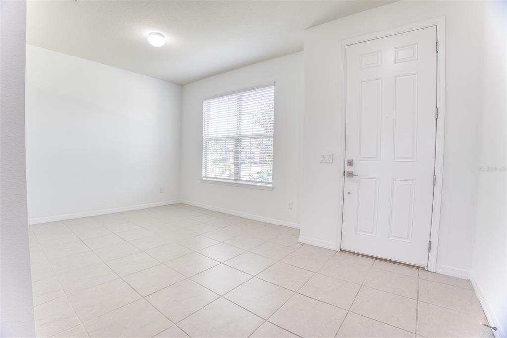 An empty room with white walls, tile flooring, a window with blinds, and a door — 5270 BRYDON WOODS CIRCLE, ST CLOUD, FL