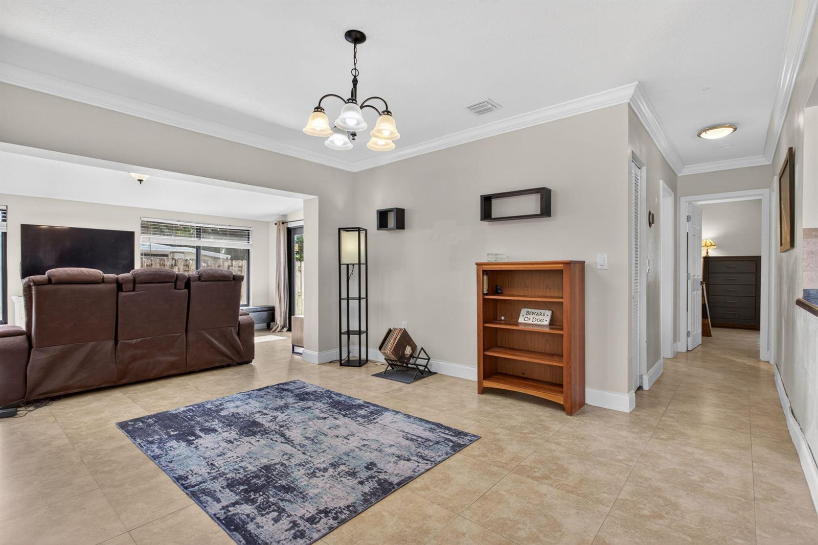 A living room features tile flooring, a blue area rug, and a wooden bookshelf — 1914 NE 53rd Court, Pompano Beach FL 33064, POMPANO BEACH, FL