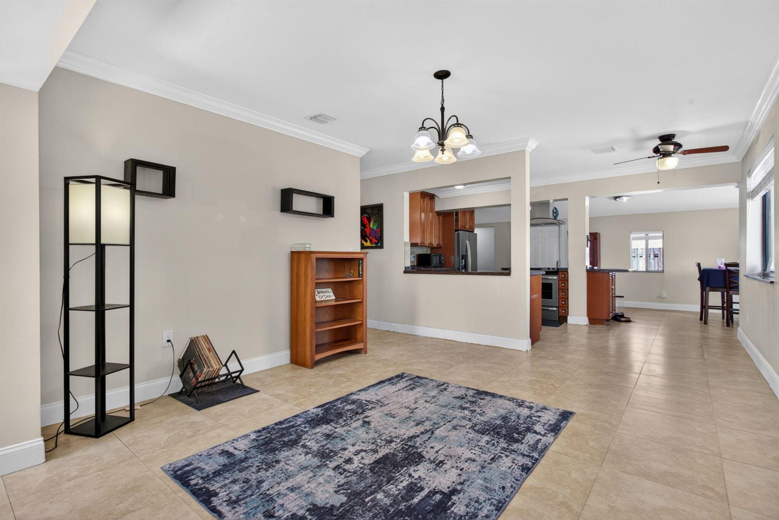 A living area with tile floors, a rug, a bookshelf, and an open kitchen pass-through — 1914 NE 53rd Court, Pompano Beach FL 33064, POMPANO BEACH, FL