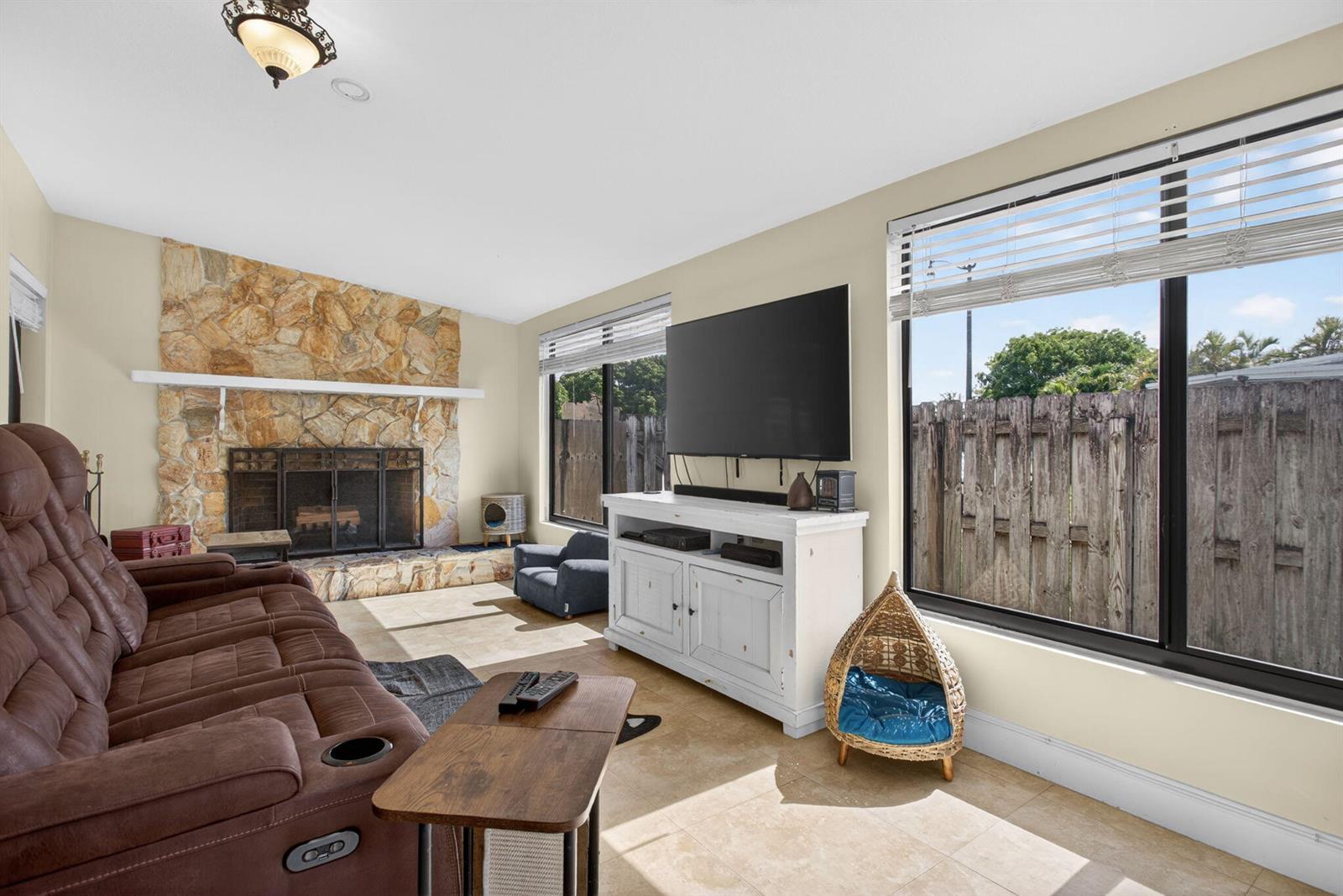 A living room features a stone fireplace, a brown recliner, and a large television console — 1914 NE 53rd Court, Pompano Beach FL 33064, POMPANO BEACH, FL