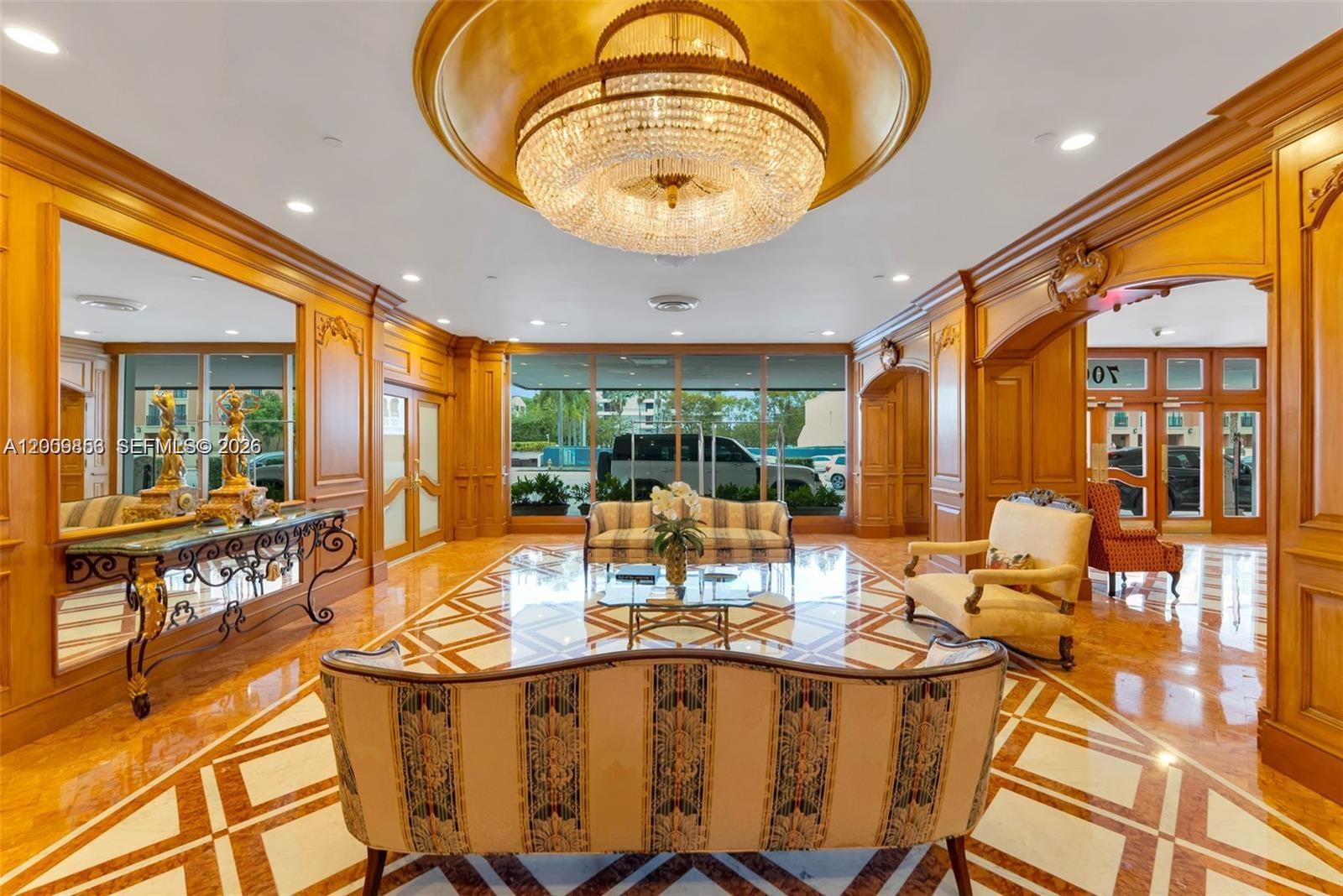 A formal lobby features wood paneling, a large crystal chandelier, and patterned marble flooring — 700 Biltmore Way # 504, Coral Gables FL 33134, CORAL GABLES, FL
