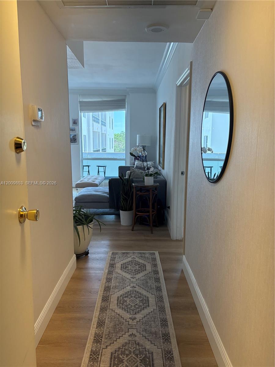 A hallway with a runner rug leads into a living room with a balcony view — 700 Biltmore Way # 504, Coral Gables FL 33134, CORAL GABLES, FL