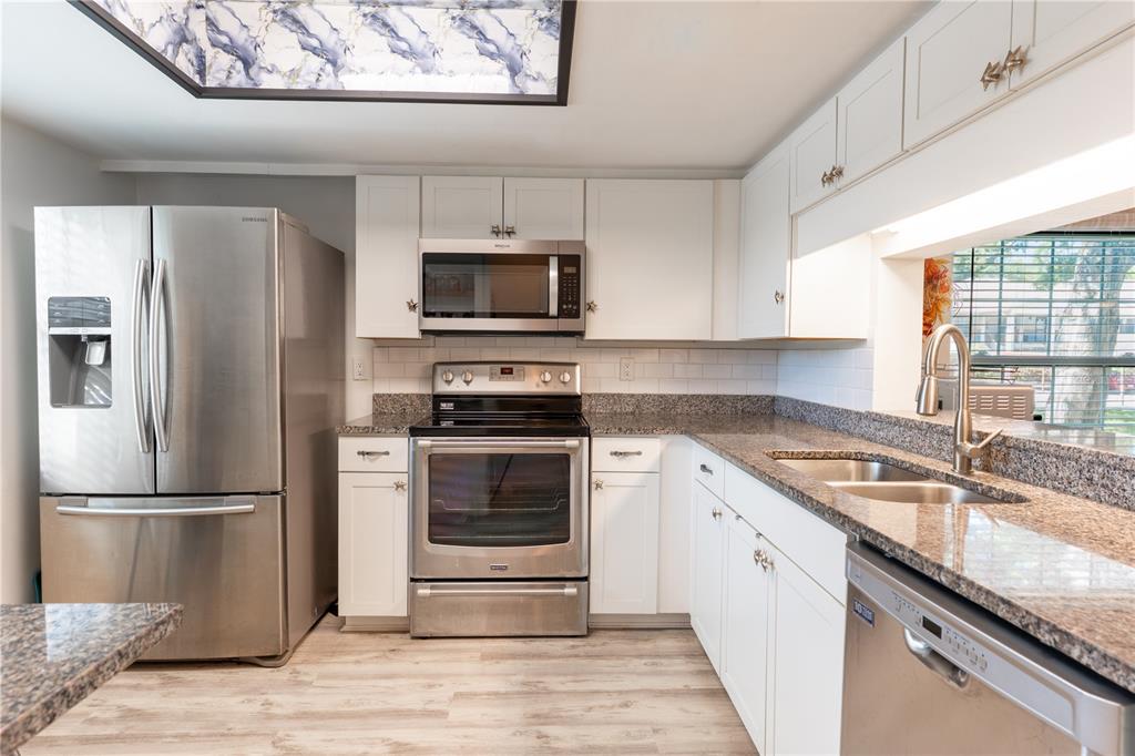 A kitchen with white cabinets, stainless steel appliances, and granite countertops — 2170 ELM STREET UNIT 901, DUNEDIN, FL