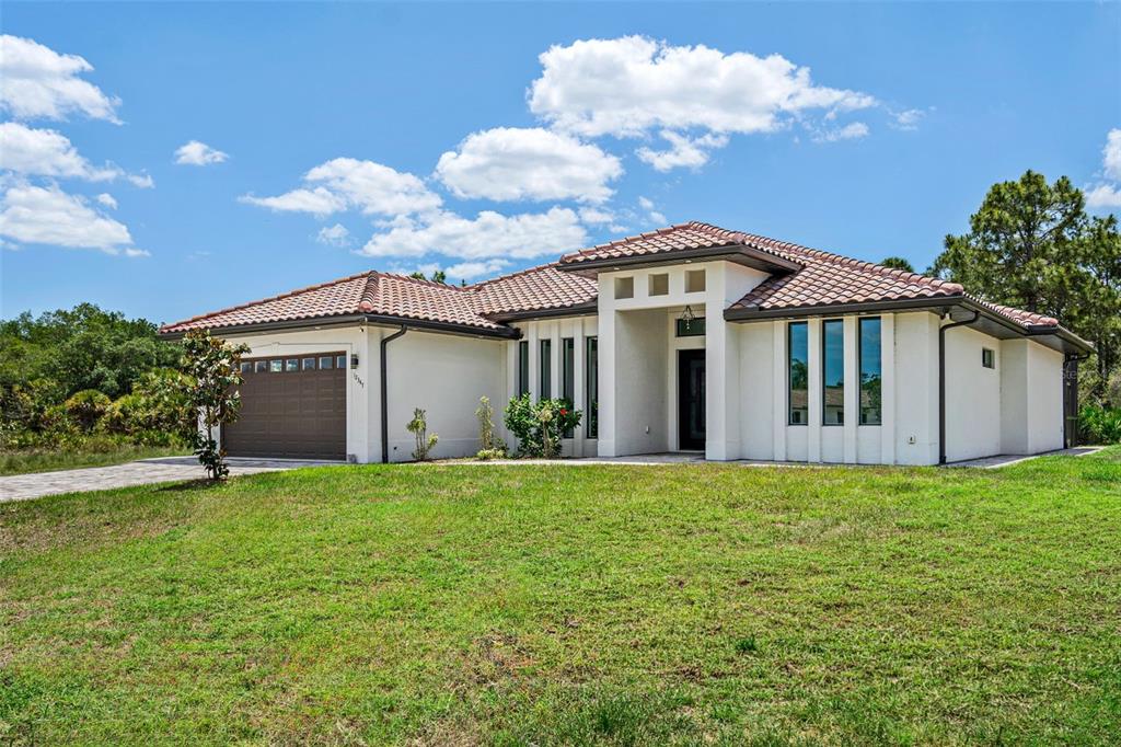 A single-story house with a tiled roof, white stucco exterior, and a two-car garage — 12347 DURANGO AVENUE, NORTH PORT, FL