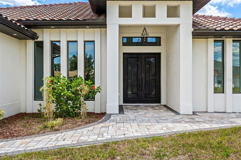 The exterior of a modern home features a double front door and a paved walkway — 12347 DURANGO AVENUE, NORTH PORT, FL
