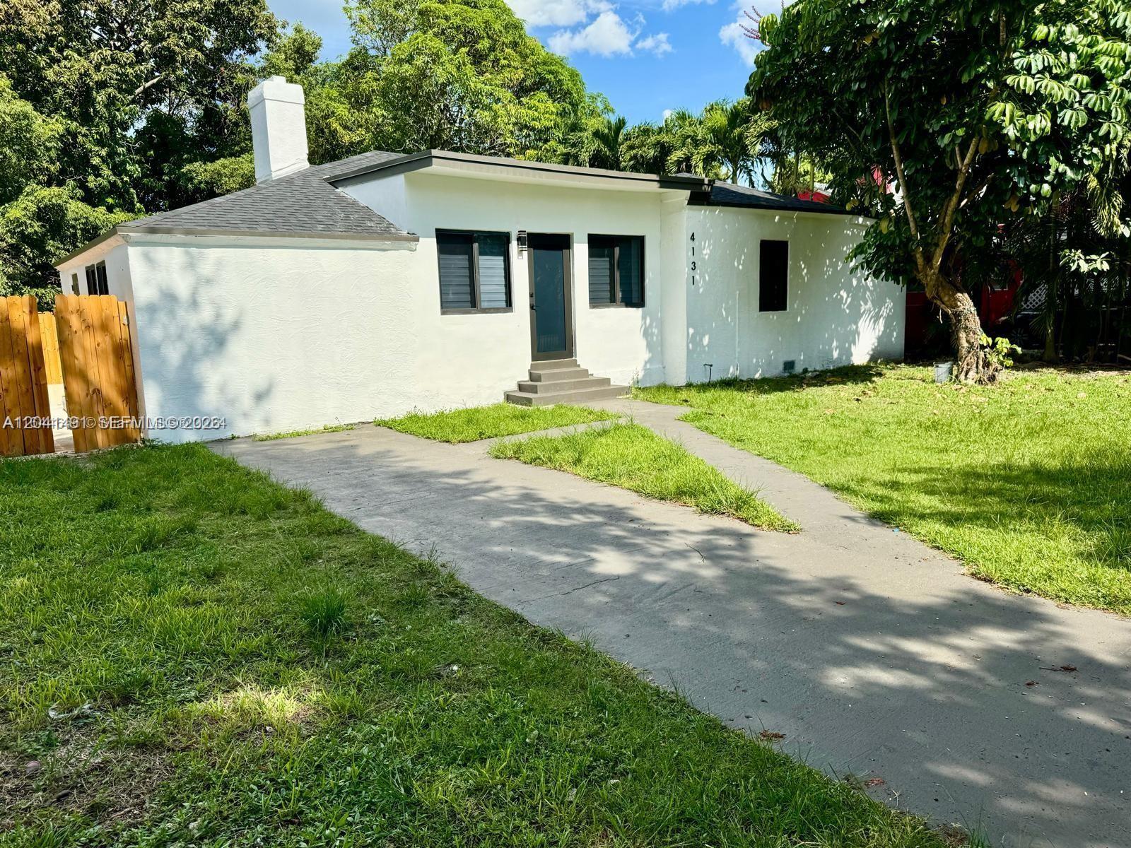 A white, single-story house with a dark roof, chimney, and a concrete driveway — 4131 NW 11th Pl, Miami FL 33127, MIAMI, FL