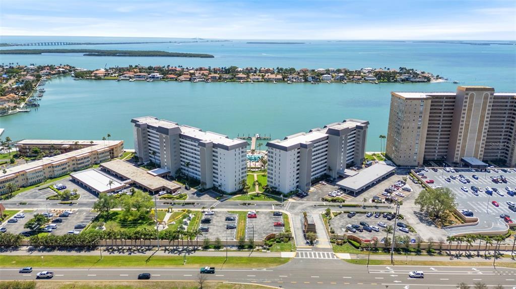 An aerial view shows two large apartment buildings situated along a waterfront with parking lots — 5130 BRITTANY DRIVE S UNIT 505, ST PETERSBURG, FL