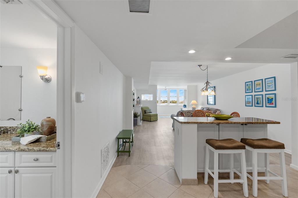 A kitchen island with bar stools overlooks a living area with a view of water — 5130 BRITTANY DRIVE S UNIT 505, ST PETERSBURG, FL
