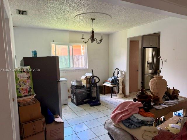 A cluttered dining area features a chandelier, tile flooring, and a view into the kitchen — 8001 NW 3rd Pl, Margate FL 33063, MARGATE, FL