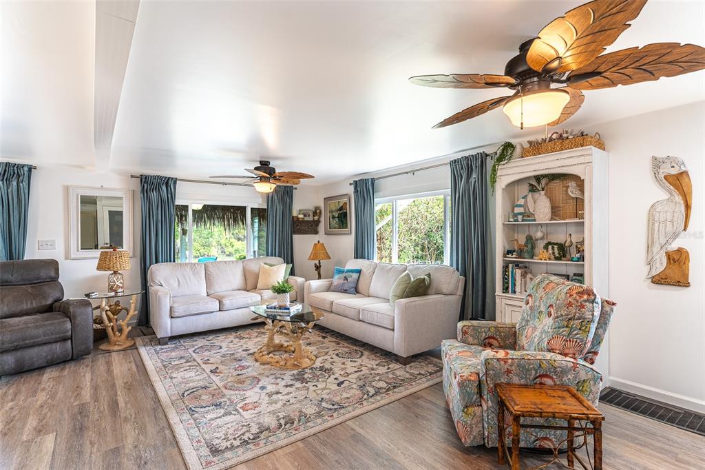 A living room features two sofas, an armchair, a patterned rug, and palm-leaf ceiling fans — 1818 BLUE LAKE DRIVE, LAKELAND, FL