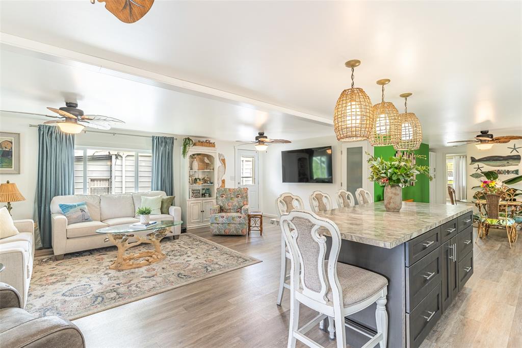 An open-concept living room and kitchen featuring a large island, pendant lights, and coastal decor — 1818 BLUE LAKE DRIVE, LAKELAND, FL