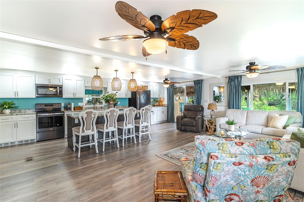 An open-concept living room and kitchen with white cabinetry, a kitchen island, and ceiling fans — 1818 BLUE LAKE DRIVE, LAKELAND, FL