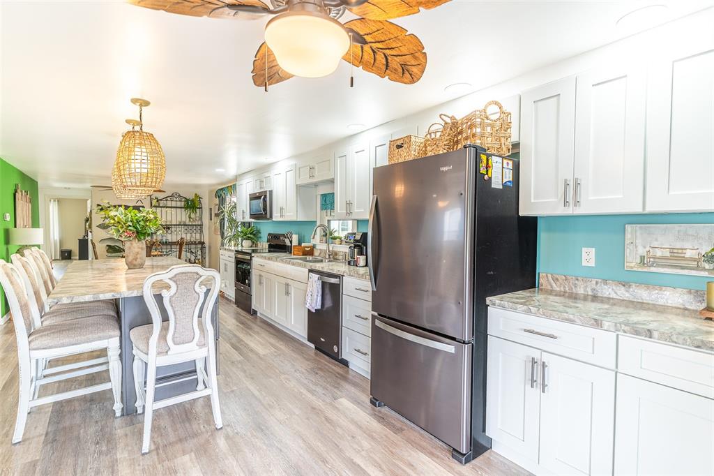 A kitchen features white cabinets, a dark refrigerator, and a dining table with chairs — 1818 BLUE LAKE DRIVE, LAKELAND, FL
