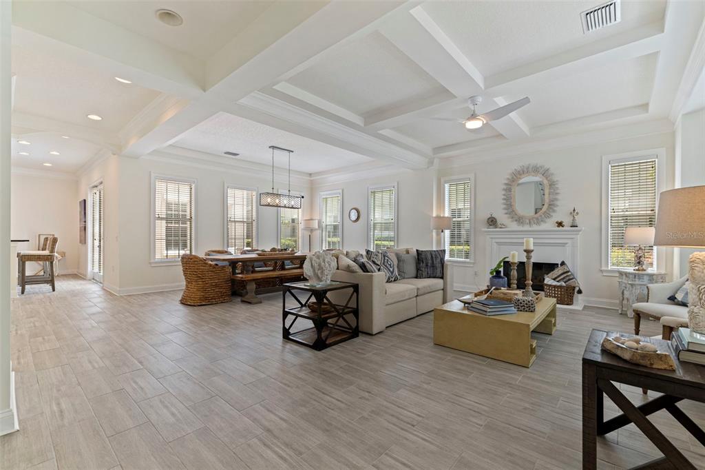 A living room features a coffered ceiling, tile flooring, a staircase, and neutral furniture — 125 COMMONWEALTH COURT N, ST PETERSBURG, FL