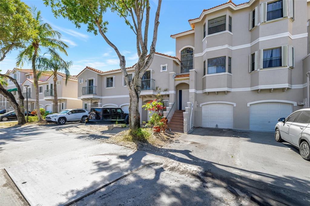 A multi-story townhouse complex with beige stucco walls, tile roofs, and attached garages — 12662 NW 14TH STREET, SUNRISE, FL