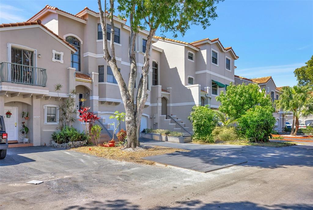 A row of multi-story townhouses with beige stucco exteriors and tile roofs under a blue sky — 12662 NW 14TH STREET, SUNRISE, FL