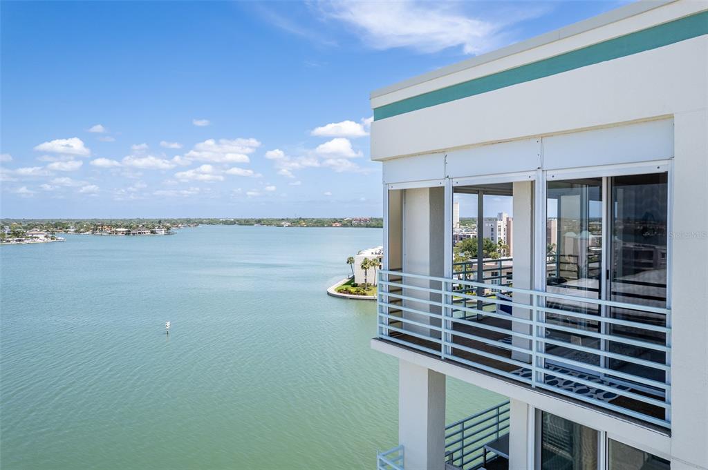 A high-angle view shows a balcony with white railings overlooking a large body of water — 7963 SAILBOAT KEY BOULEVARD S UNIT PH801, SOUTH PASADENA, FL
