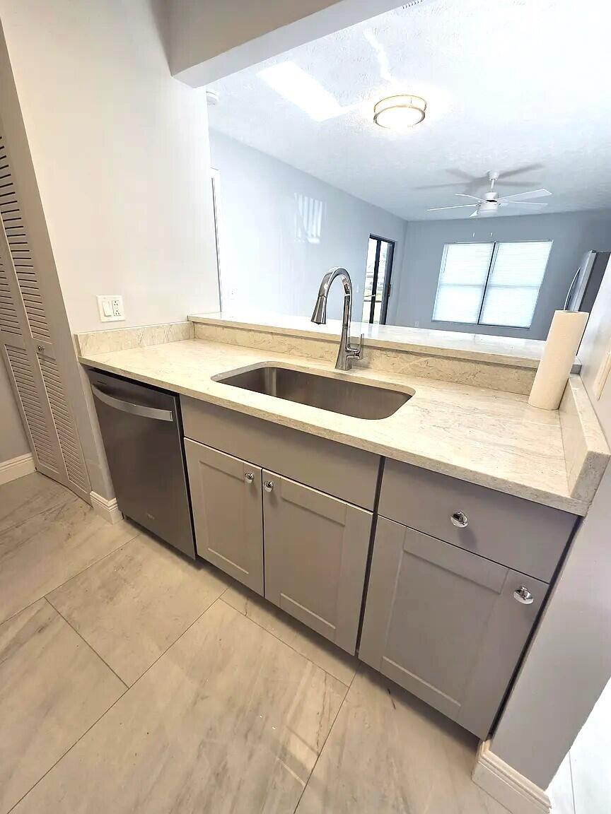 A kitchen features gray cabinets, a stainless steel sink, and light-colored stone countertops — 6551 SE Federal Highway # 104, Stuart FL 34997, STUART, FL