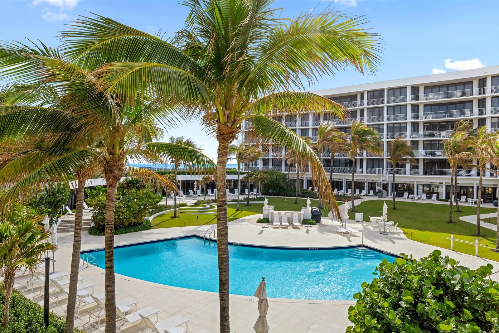 An outdoor swimming pool surrounded by palm trees and a multi-story building with balconies — 2000 S Ocean Boulevard # 107n, Palm Beach FL 33480, PALM BEACH, FL