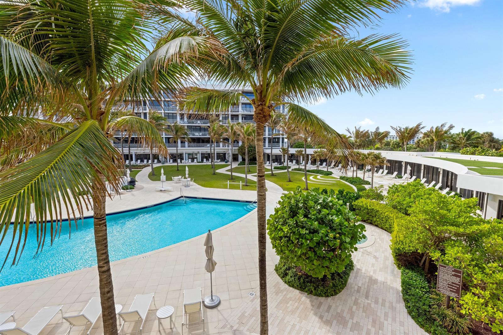 An outdoor swimming pool area with palm trees, lounge chairs, and a multi-story building — 2000 S Ocean Boulevard # 107n, Palm Beach FL 33480, PALM BEACH, FL
