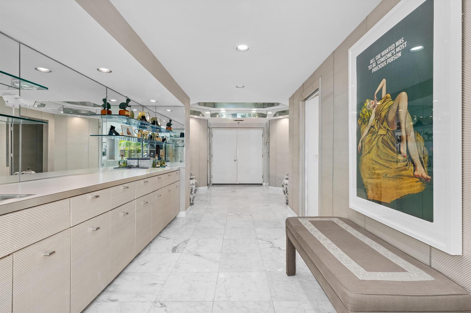 A hallway with marble floors, a long built-in cabinet, a large mirror, and framed artwork — 2000 S Ocean Boulevard # 107n, Palm Beach FL 33480, PALM BEACH, FL