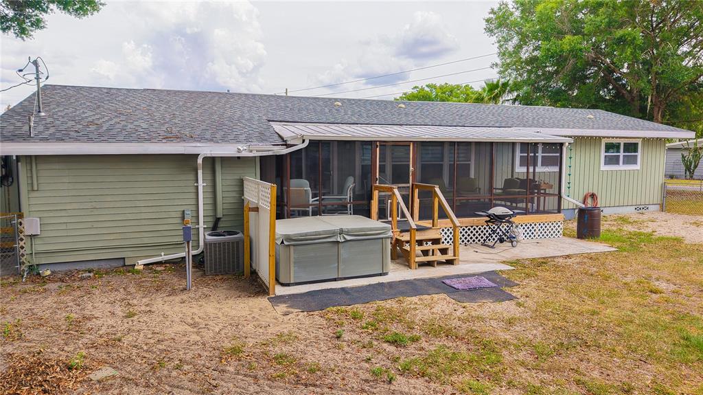 The exterior of a house features a screened-in porch, a hot tub, and a patio — 5233 HILL DRIVE, ZEPHYRHILLS, FL