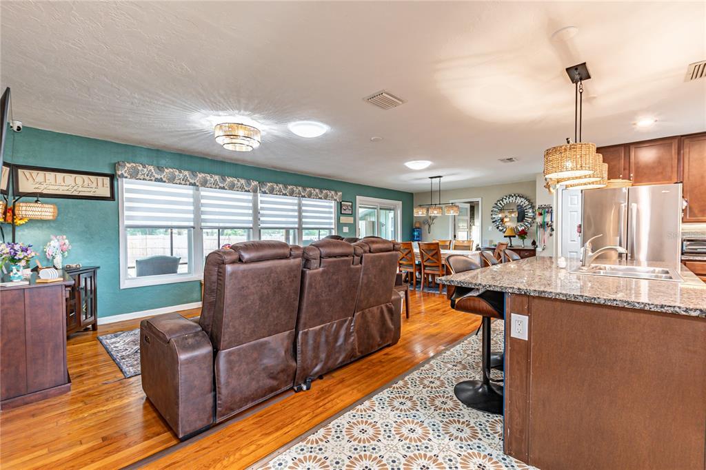 An open-concept kitchen and living area featuring a brown leather sofa and granite countertops — 5233 HILL DRIVE, ZEPHYRHILLS, FL