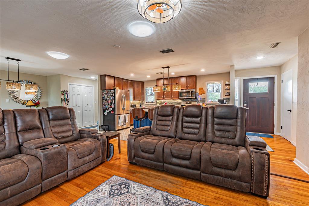 A living room with brown leather recliners opens into a kitchen with wooden cabinets — 5233 HILL DRIVE, ZEPHYRHILLS, FL