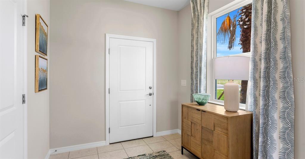 An entryway features a white door, a wooden console table, and a window with curtains — 10168 MORNING MEADOWLARK TRAIL, PARRISH, FL