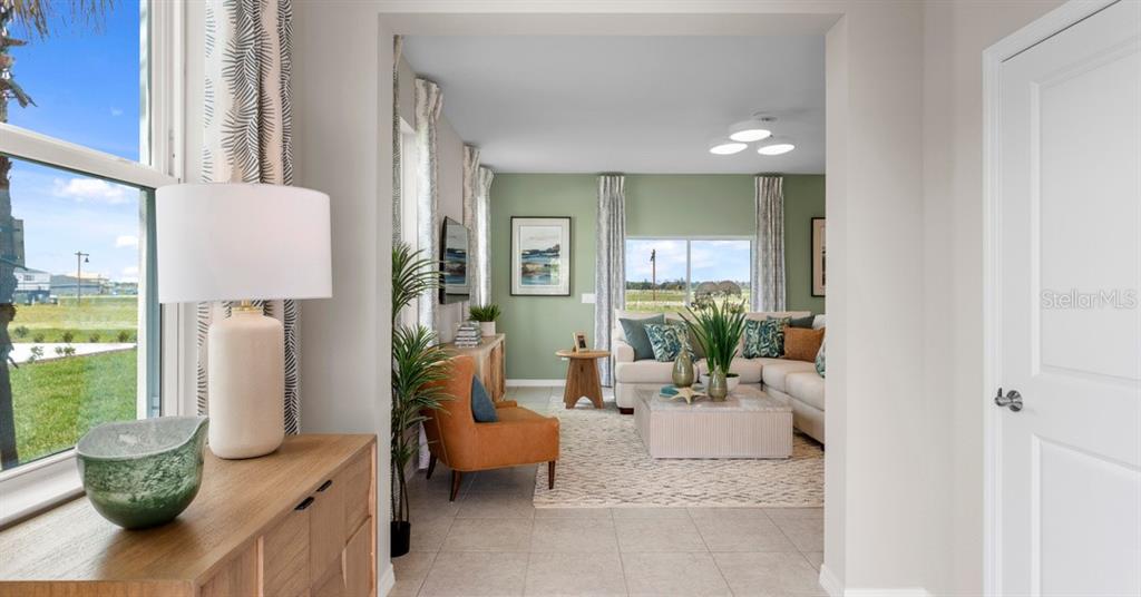 A view from a hallway looks into a living room with green walls and furniture — 10168 MORNING MEADOWLARK TRAIL, PARRISH, FL