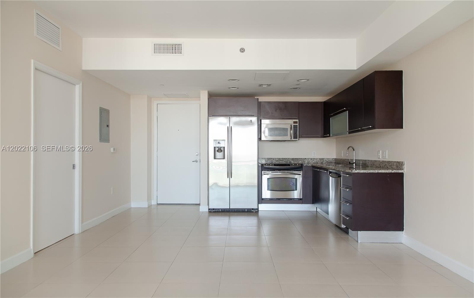 This kitchen features dark wood cabinetry, stainless steel appliances, and light-colored tile flooring — 951 Brickell Ave # 4009, Miami FL 33131, MIAMI, FL