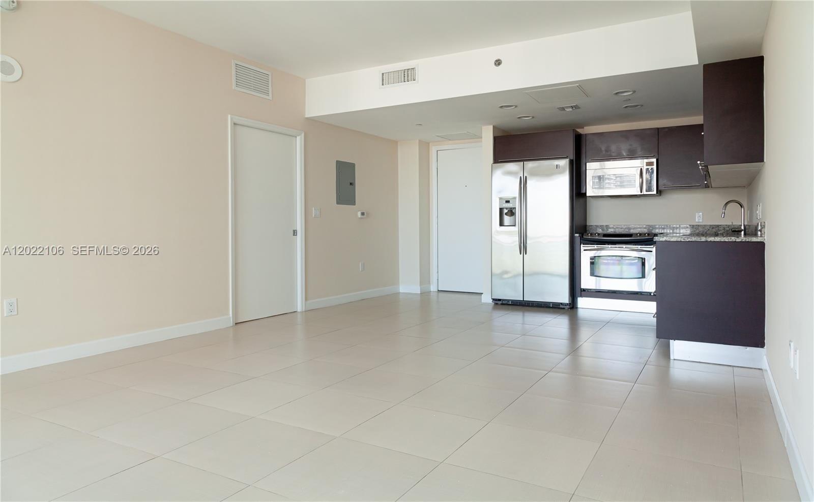 An open-concept kitchen and living area features light tile flooring and dark wood cabinetry — 951 Brickell Ave # 4009, Miami FL 33131, MIAMI, FL