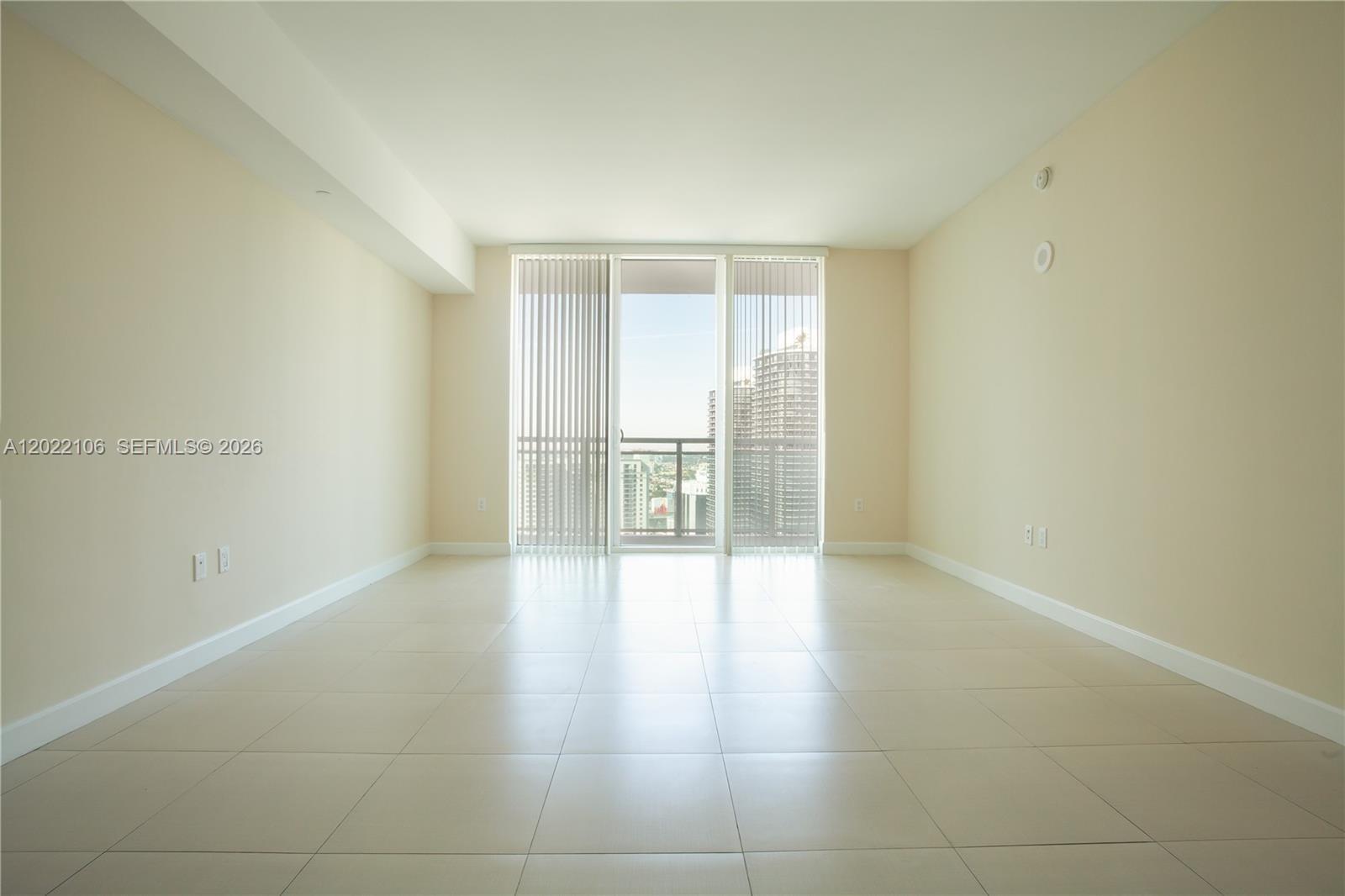 An empty room features light-colored tile flooring, beige walls, and a balcony with city views — 951 Brickell Ave # 4009, Miami FL 33131, MIAMI, FL