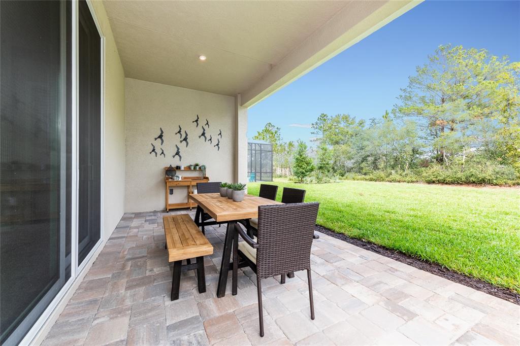 A covered patio features a wooden dining table, wicker chairs, and sliding glass doors — 1629 LAKE RESERVE DRIVE, DELAND, FL