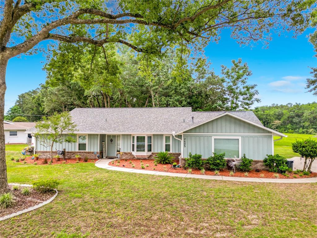 A light blue, single-story house with a brick base and a curved walkway in front — 2405 SE 52ND AVENUE, OCALA, FL