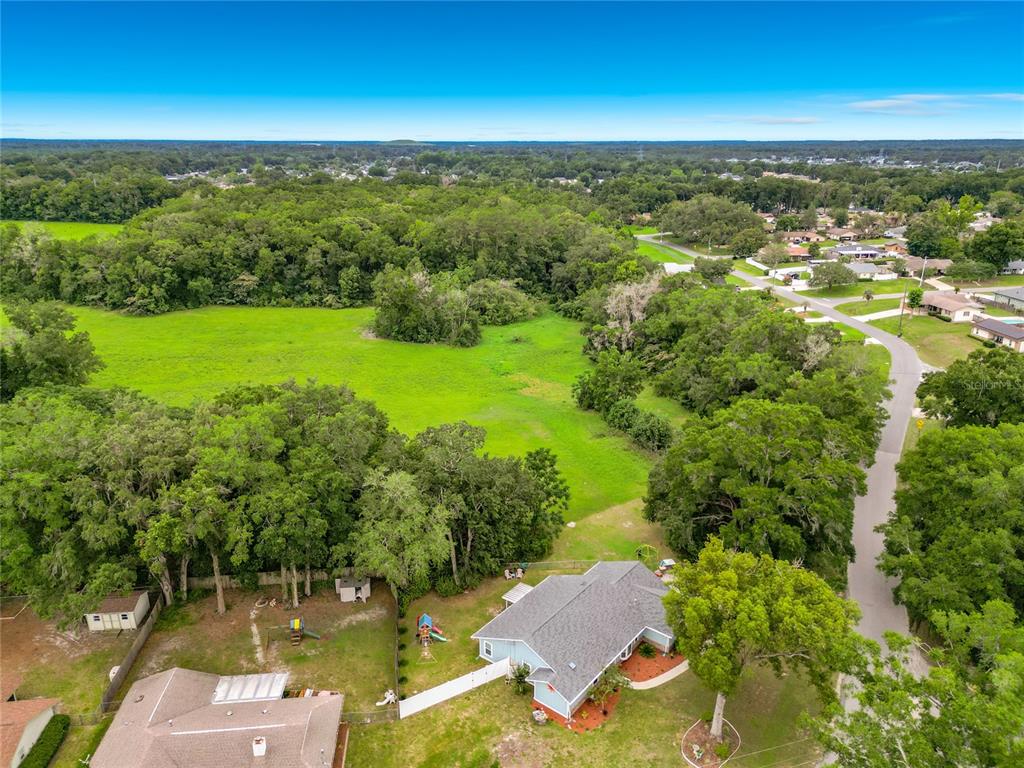An aerial view shows a house with a gray roof surrounded by trees and fields — 2405 SE 52ND AVENUE, OCALA, FL