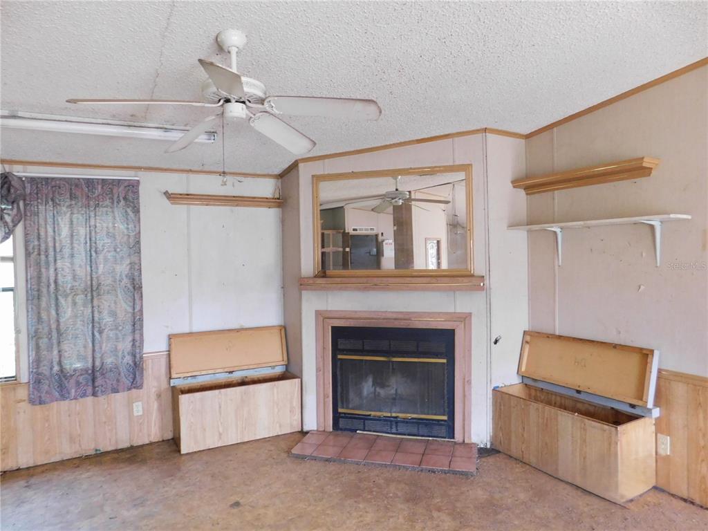 A living room features a fireplace, a large mirror, and two wooden storage benches — 2634 SEA OATS CIRCLE N, LAKELAND, FL