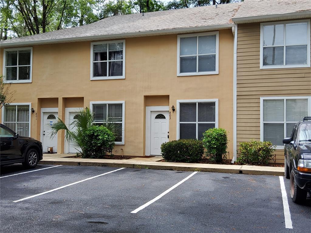 A two-story townhouse exterior with tan stucco, brown siding, and a paved parking lot — 4415 SW 34TH STREET UNIT 803, GAINESVILLE, FL