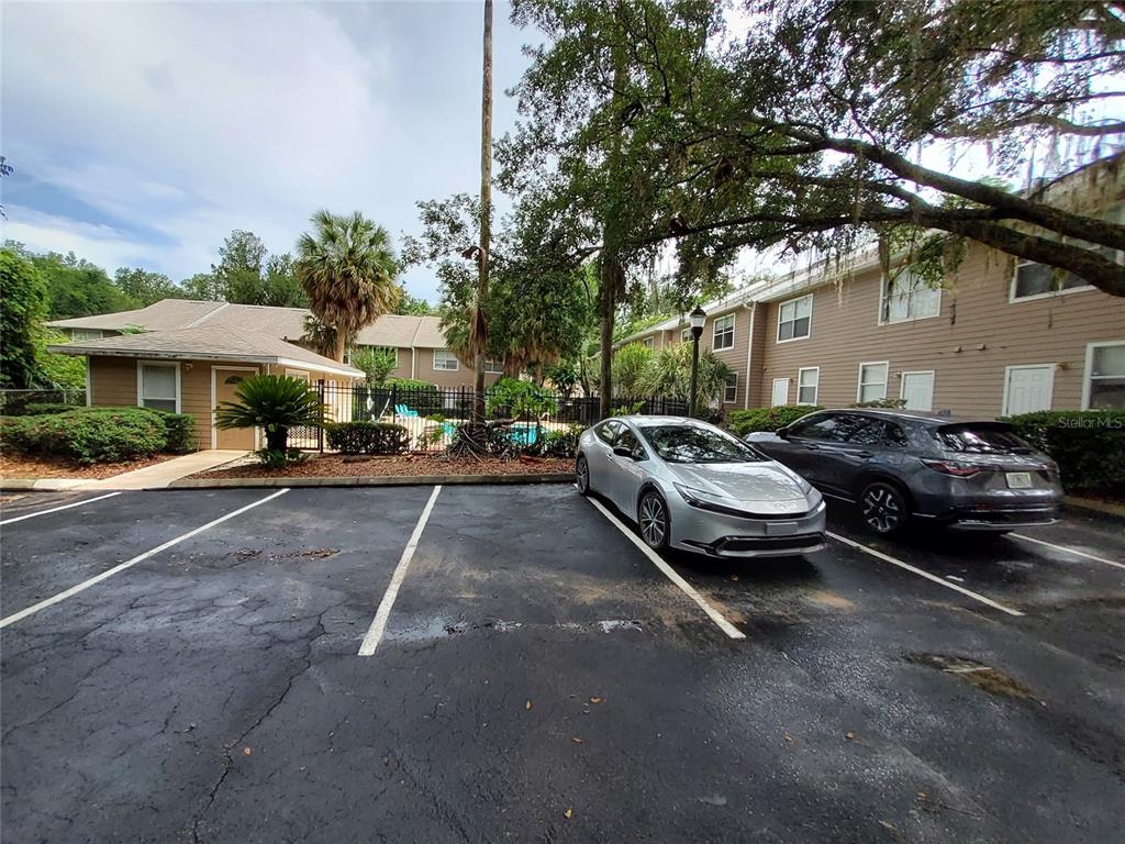 A parking lot sits in front of a multi-story apartment building and a swimming pool — 4415 SW 34TH STREET UNIT 803, GAINESVILLE, FL
