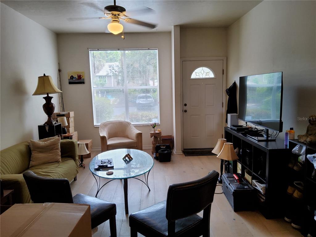 A living room features a sofa, glass coffee table, armchairs, and a television on a stand — 4415 SW 34TH STREET UNIT 803, GAINESVILLE, FL
