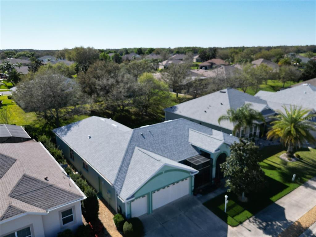 An aerial view shows the exterior of a suburban house with a gray shingled roof — 25517 LAUREL VALLEY ROAD, LEESBURG, FL