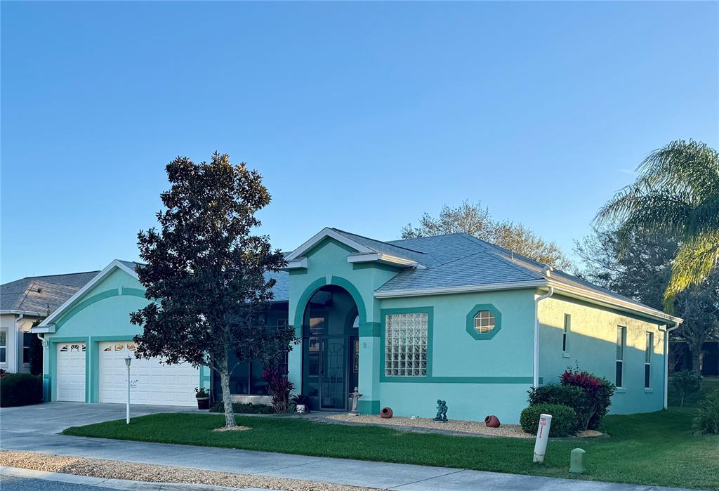A teal single-story house features a two-car garage, a covered entryway, and a glass-block window — 25517 LAUREL VALLEY ROAD, LEESBURG, FL