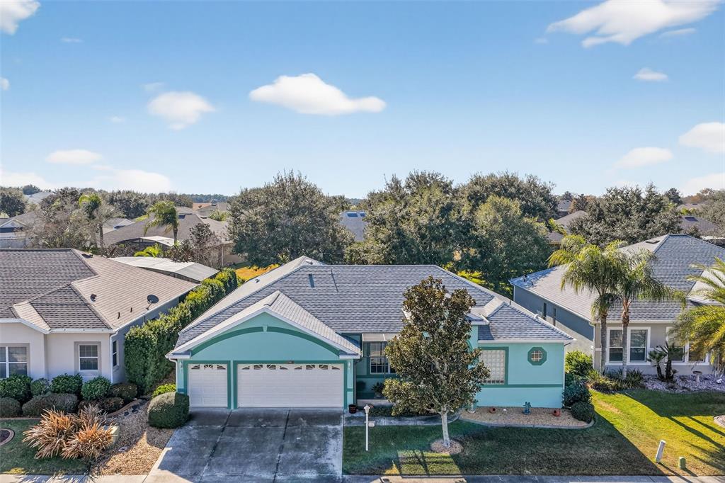 An aerial view shows a light blue single-story house with a two-car garage and trees — 25517 LAUREL VALLEY ROAD, LEESBURG, FL