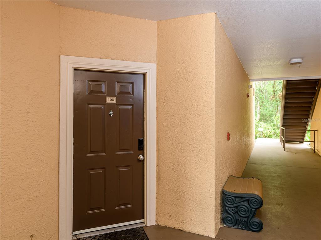 A brown front door labeled 108 is located in an outdoor apartment building corridor — 5125 PALM SPRINGS BOULEVARD UNIT 7108, TAMPA, FL
