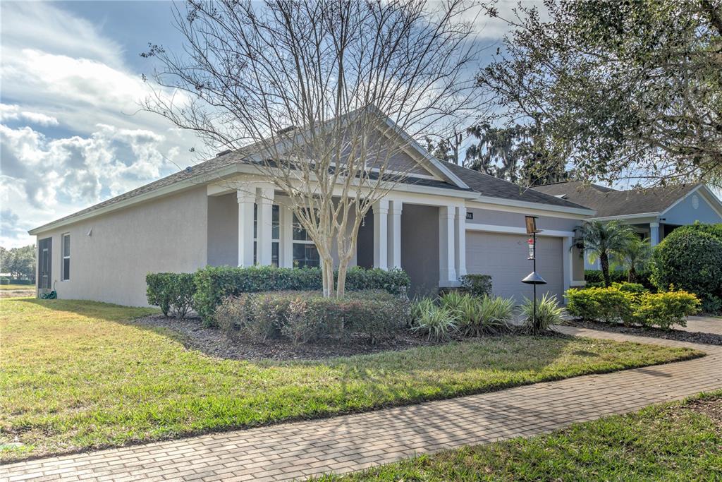 A single-story house with a beige stucco exterior, a two-car garage, and a brick walkway — 19744 FORT KING RUN, BROOKSVILLE, FL