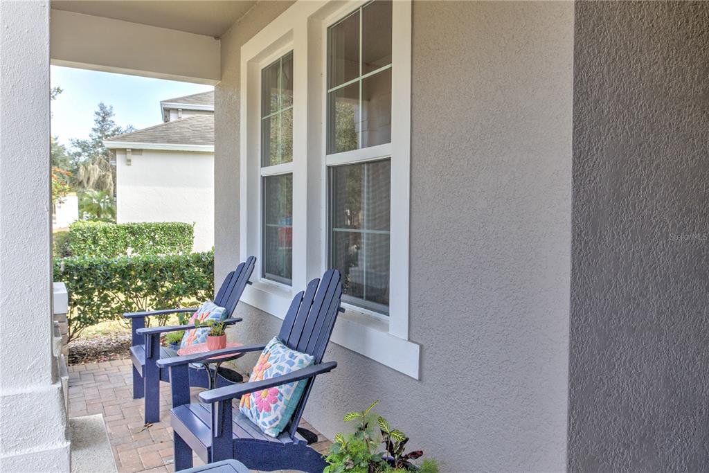 A covered porch features two blue Adirondack chairs on a brick paver floor — 19744 FORT KING RUN, BROOKSVILLE, FL