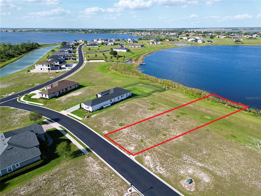 An aerial view shows a vacant rectangular lot situated next to a lake and houses — 283 SPINNAKER COURT, AUBURNDALE, FL
