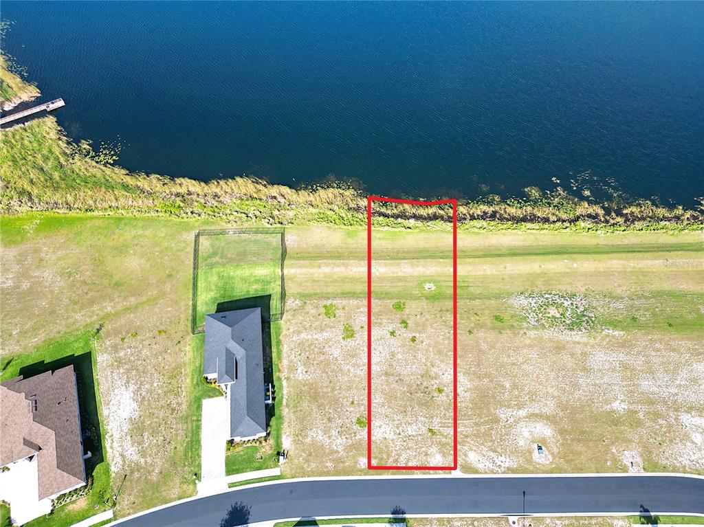 An aerial view shows a rectangular vacant lot outlined in red bordering a lake — 283 SPINNAKER COURT, AUBURNDALE, FL